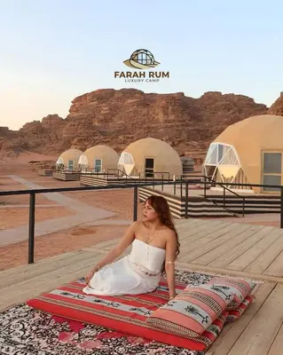 a woman sitting on a rug in the desert at FARAH RUM LUXURY CAMP & Bubbles Hotel in Wadi Rum
