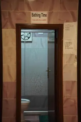 a bathroom with a toilet and a sign that says bathing time at Petra sharing room in Petra