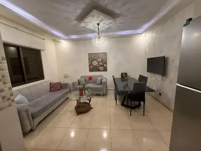 a living room with a couch and a table at Furnished luxuries Apartment with a Stunning View in Amman