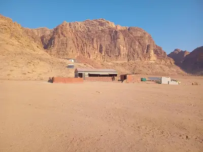 a building in the desert with a mountain in the background at Ayed Wadi Rum camp in Wadi Rum