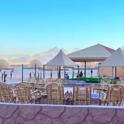 a group of chairs and tables and umbrellas on a beach at Desert Oasis in Wadi Rum Village - Cozy Lodge Room in Aqaba