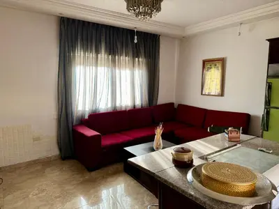 a living room with a red couch and a table at Fully Furnished apartment for rent in Amman Khalda in Amman