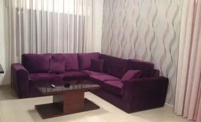 a purple couch in a living room with a coffee table at luxury apartment in amman, abdoun in Amman