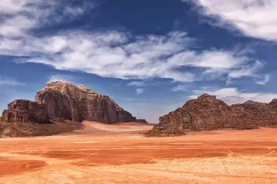 a desert with two large rocks and a blue sky at faisal wadi rum in Wadi Rum