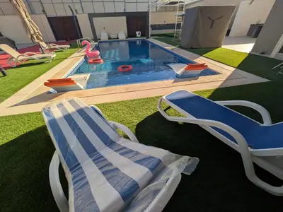 a backyard with a pool with a chair and a swing at Noorhan Private Luxury Layover Villa - 10 Minutes to Airport in Amman