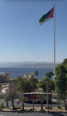a flag on a pole in a parking lot at السلام للشقق الفندقية peace hotel apartments in Aqaba