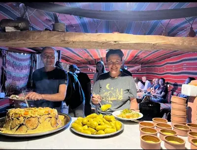 two men standing in front of a table with plates of food at Peace House in Wadi Musa
