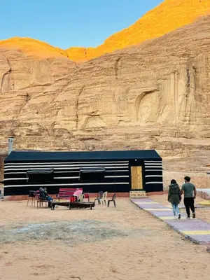 two people walking in front of a building in the desert at Lunar scape haven in Wadi Rum