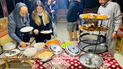 a group of people standing around a table with food at Lunar scape haven in Wadi Rum