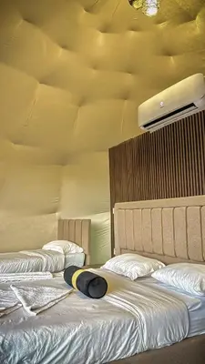 two beds with white sheets and a surfboard on them at Wadi Rum Sila Camp in Wadi Rum