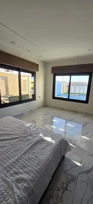 a bedroom with two windows and a bed in it at شاليه المهرة in Murayjimat Ibn Ḩāmid