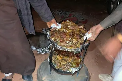 a group of people cooking food on a grill at Nomad Heights Authentic Bedouin Cave Experience in Wadi Rum in Wadi Rum