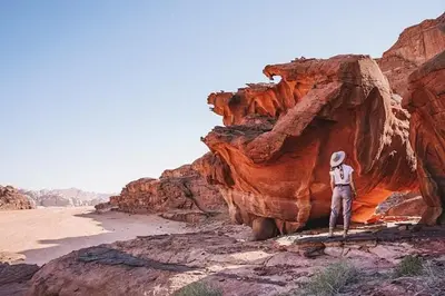 a man standing on a bridge in front of a rock formation at Nomad Heights Authentic Bedouin Cave Experience in Wadi Rum in Wadi Rum