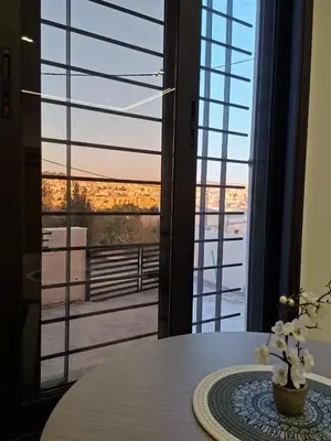 a table with a vase of flowers on a table with a window at Jeeso Hotel in Jerash