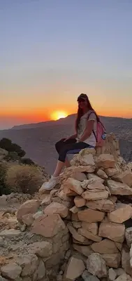 a woman sitting on top of a rock wall at sunset at TOWER Hotel in Dana