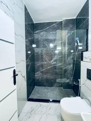 a bathroom with a toilet and a glass shower at Zurich Furnished Apartments in Al Mafraq
