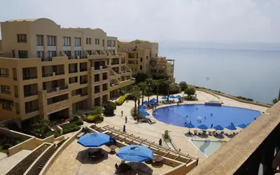 a view of a swimming pool with umbrellas and buildings at Family WeekEnds Getaways at Samarah Resort Studio in Sowayma