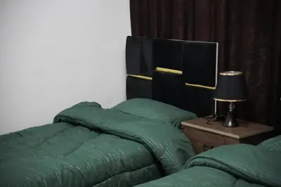 a bedroom with two green beds and a table with a lamp at Petra entrance Apartment in Petra