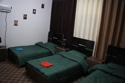 a room with three green beds and a couch at Petra Visitor Center Apartment in Petra