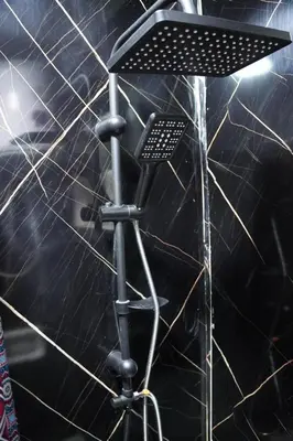 a stand up shower in a room with a black wall at Petra Visitor Center Apartment in Petra