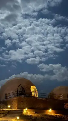 a domed building with a cloudy sky at night at Gmal Rum Cano in Wadi Rum