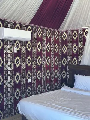 a bedroom with a bed and a wall with a canopy at Sana Rum Luxury Camp in Wadi Rum