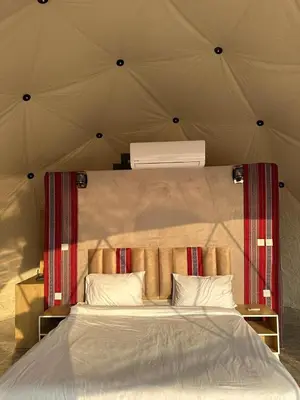 a bed in a tent with a white bedspread and pillows at Sana Rum Luxury Camp in Wadi Rum