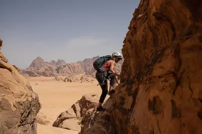 a person with a backpack on a rock in the desert at Rum Adventures Hostel in Wadi Rum