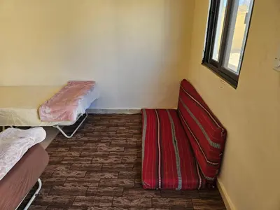 a room with a bed and a chair and a window at Rum Adventures Hostel in Wadi Rum