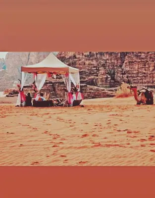 a group of people sitting under a tent in the desert at وادي رم in Wadi Rum
