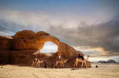 a group of people riding camels in the desert at LAVRA lUXURY CAMP in Wadi Rum