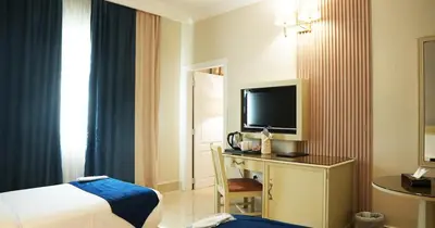 a hotel room with a bed and a desk with a television at Amman West Luxury Hotel By Azar in Amman