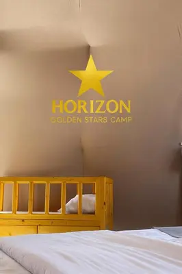 a sign with a star on the wall next to a bed at Horizon Star Golden Camp in Wadi Rum