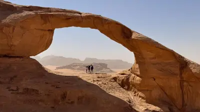 two people walking through an arch in the desert at SILENT SKY lUXURY CAMP in Wadi Rum