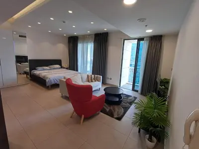 a bedroom with a bed and a red chair at Studio at Damac Jordan in Amman