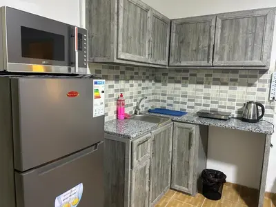 a kitchen with wooden cabinets and a stainless steel refrigerator at A double bed apartment in heart of Amman شارع سلطان الهند خلف ش عبدالله غوشه in Amman
