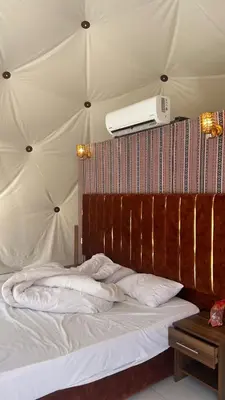 a bedroom with a white bed with a ceiling at RUM AlLIRA lUXURY CAMP in Wadi Rum