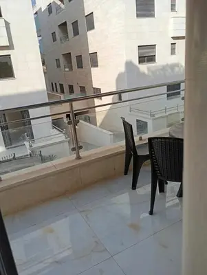 a balcony with two chairs and a table and a window at شقه مفروشه in Amman