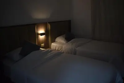a hotel room with two beds in a dark room at Al-Farouq Suites in Amman