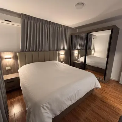 a bedroom with a white bed and a large mirror at Al-Farouq Suites in Amman