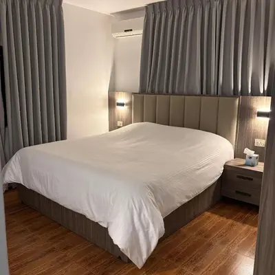 a bedroom with a large bed with white sheets at Al-Farouq Suites in Amman