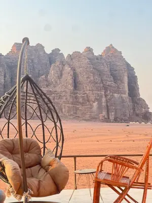 a view of a beach with two chairs and a mountain at Al-Najm Coastal Camp Rum in Wadi Rum