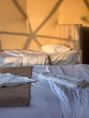 two beds in a room with towels on them at Al-Najm Coastal Camp Rum in Wadi Rum
