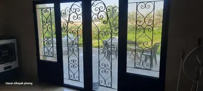 two glass doors with a view of a yard at استراحة الباشا albash farm stay in Al Karāmah