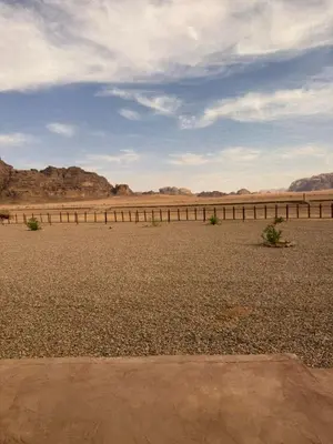 a desert with a fence and mountains in the background at Ayloulcamp in Disah