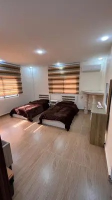 two beds in a large room with wooden floors at شقة مفروشة apartment amman alnuzzha in Amman