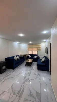 a living room with blue couches and a table at شقة مفروشة apartment amman alnuzzha in Amman