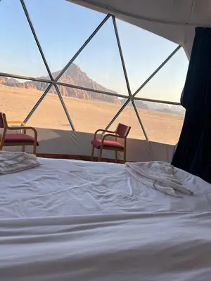 a bed and two chairs in a tent in the desert at Moon Camp Wadi Rum in Wadi Rum