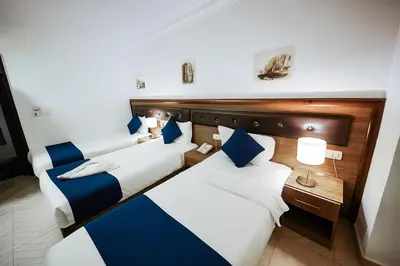 three beds in a hotel room with blue and white at Corner View Hotel in Wadi Musa