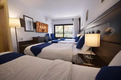 a hotel room with three beds and a window at Corner View Hotel in Wadi Musa